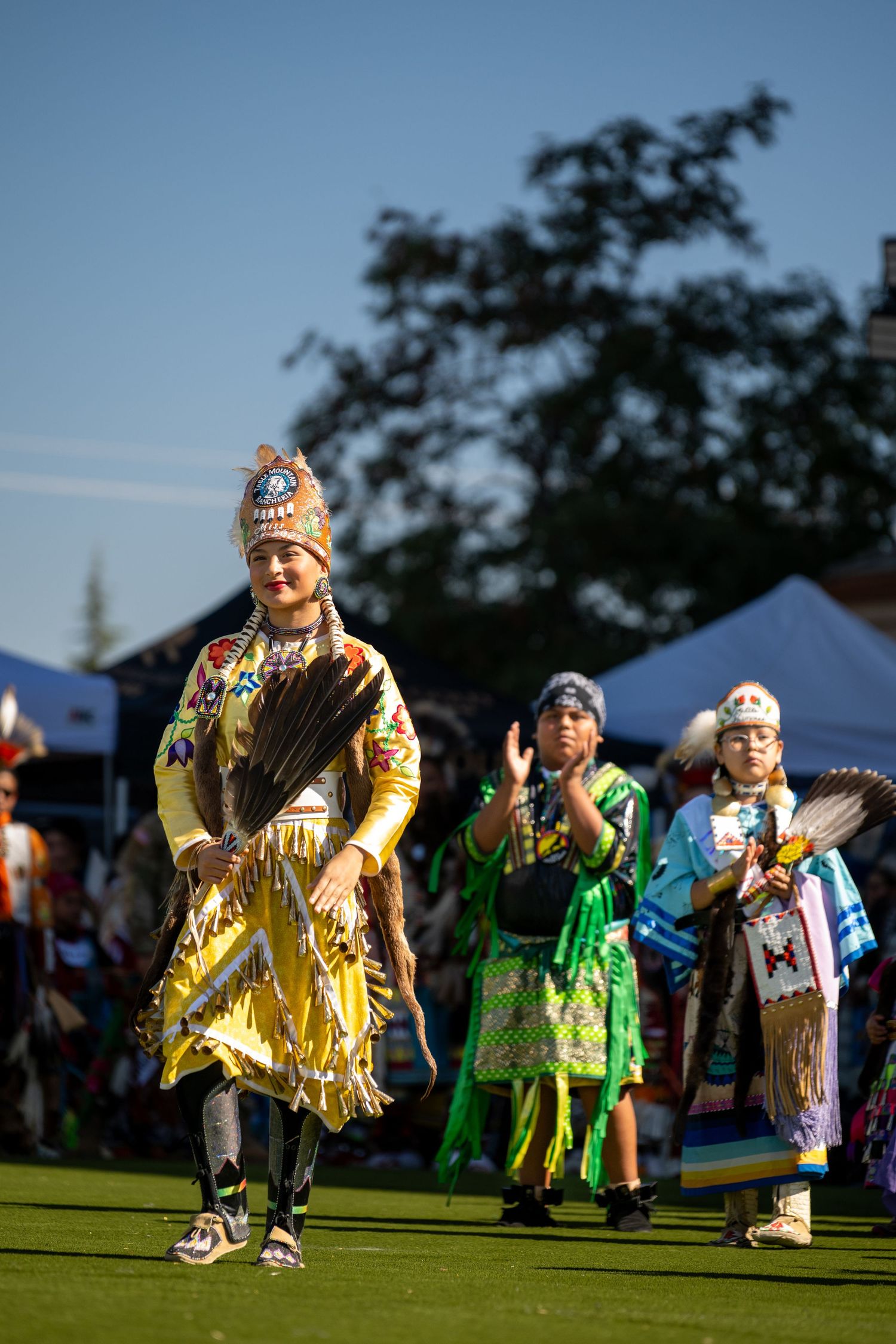 Traditional Native American dancers perform in colorful regalia at an outdoor event.