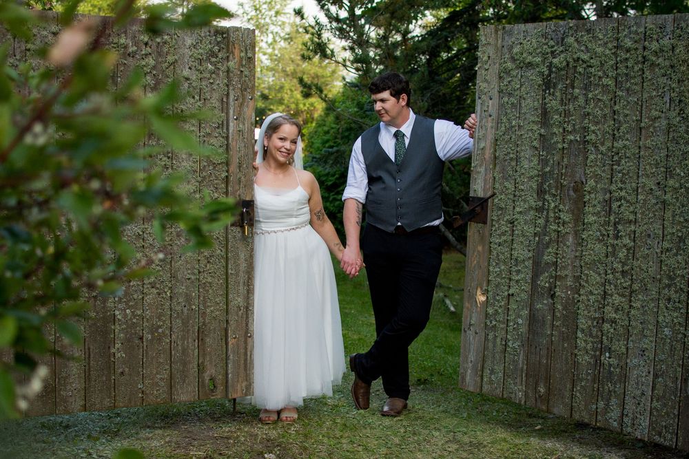 Couple poses for romantic photos along a rustic wooden fence during their wedding.