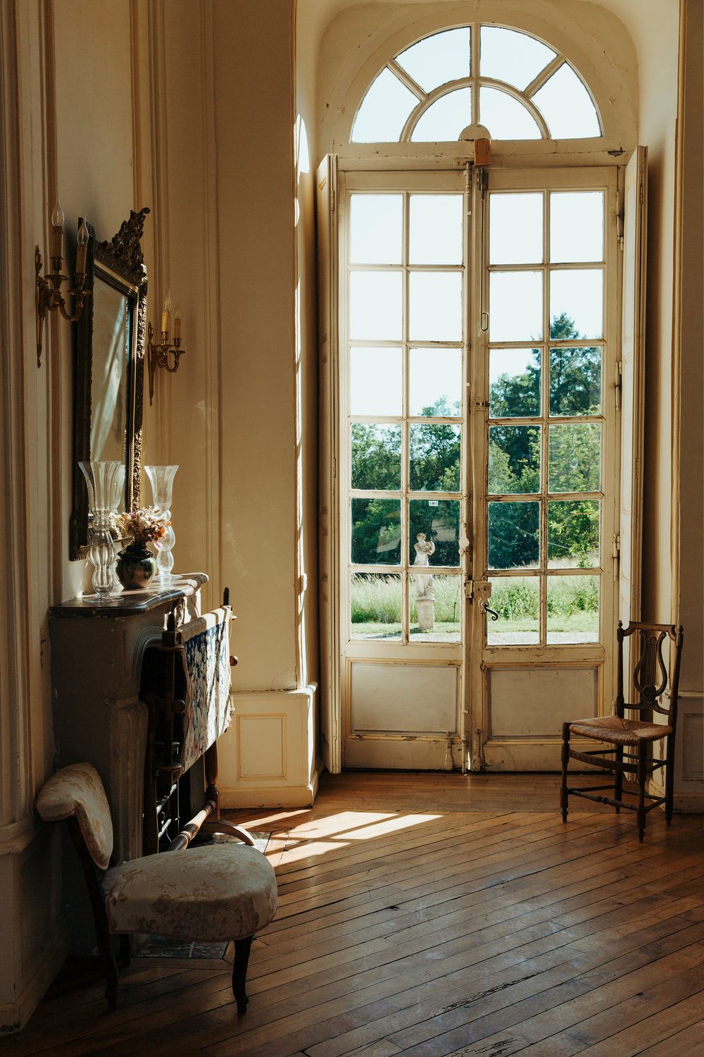 Elegant interior room with arched windows and hardwood floors bathed in natural sunlight.