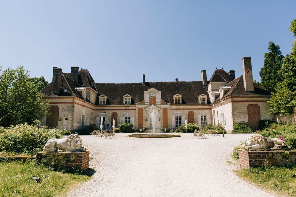 Panoramic view of a stately manor house with classic architecture against blue sky.