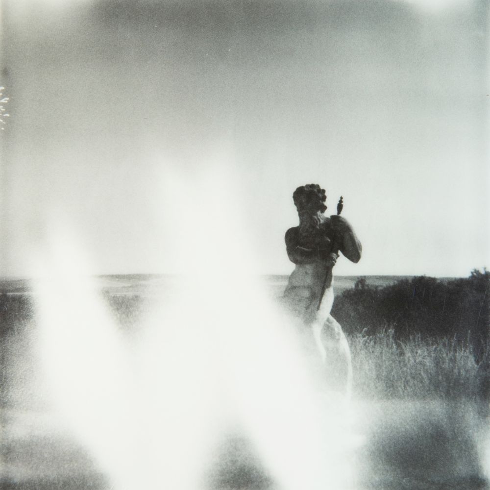 A silhouetted figure photographed through misty light in an outdoor setting.