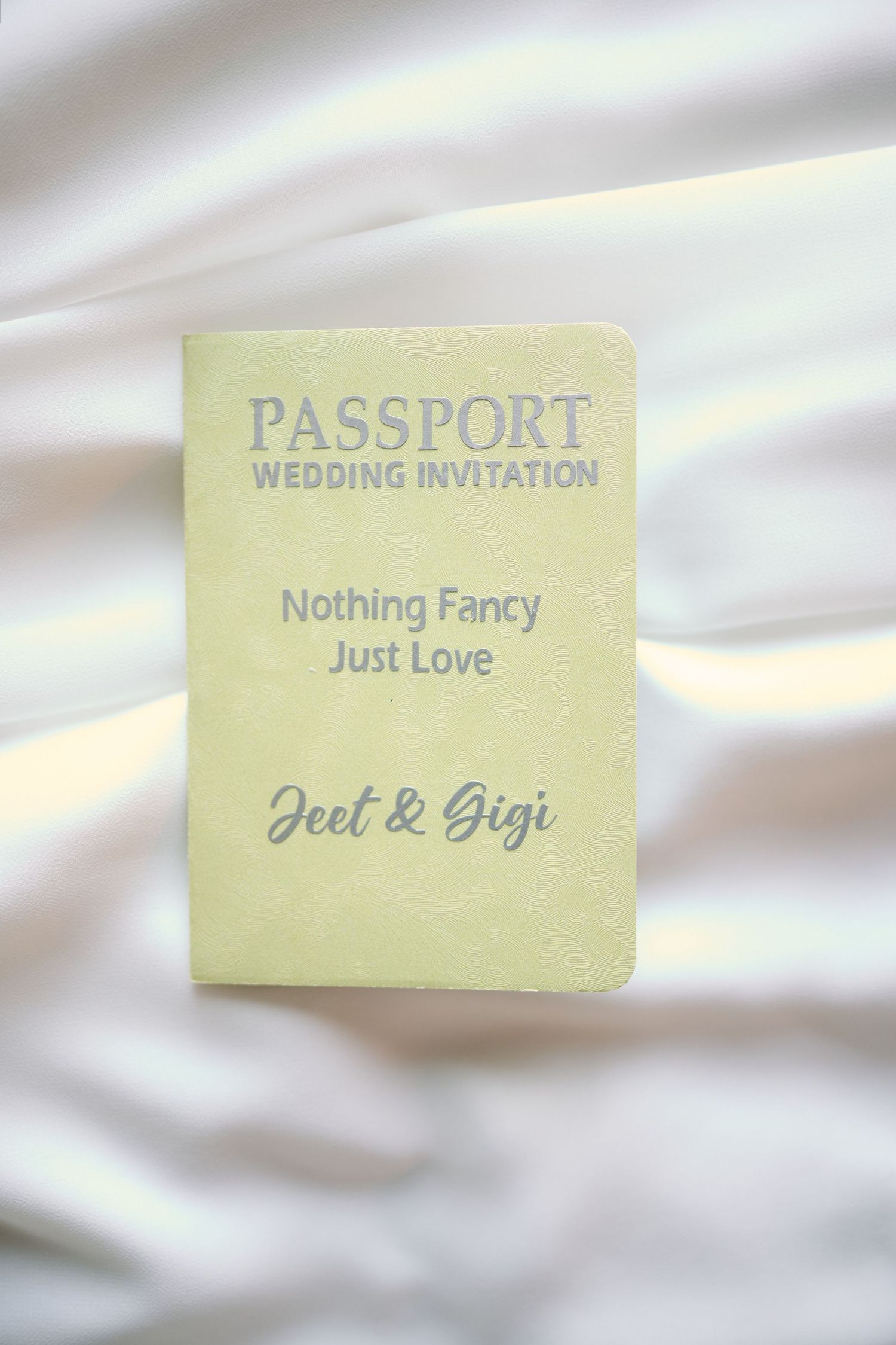 Wedding invitation passport design with text 'Nothing Fancy Just Love' for Jeet and Gigi on pale yellow paper.