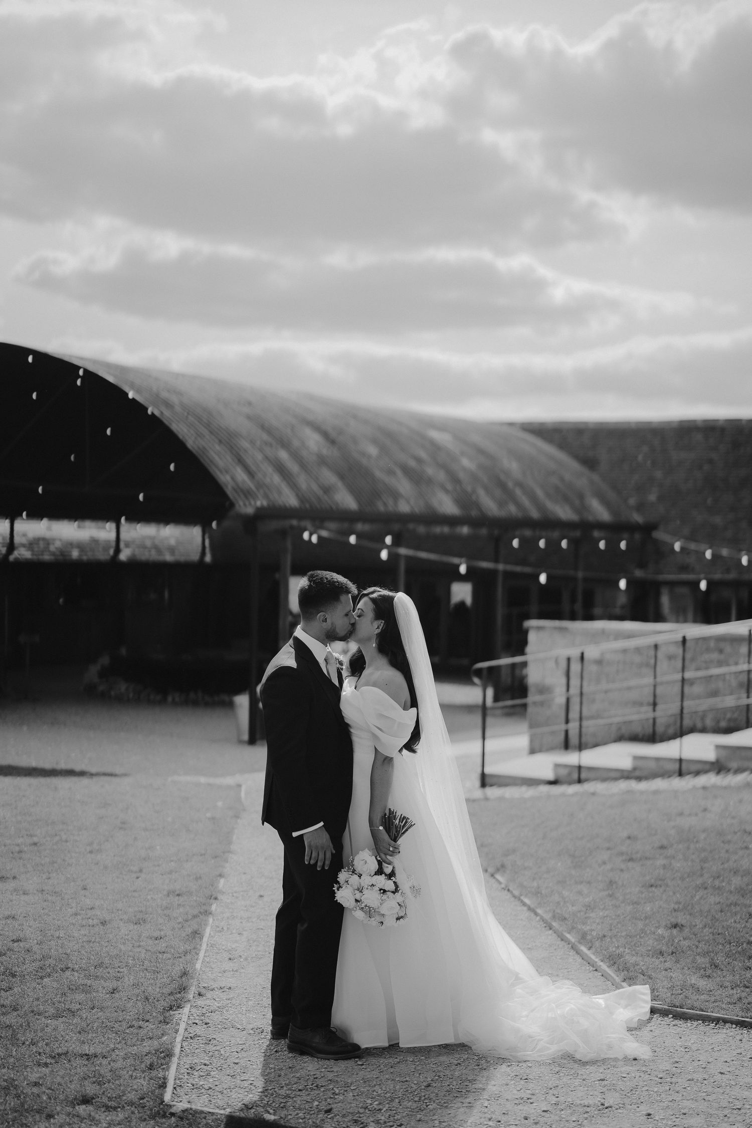 bride and groom kissing infront of barn at yardspace old gore in cirencester