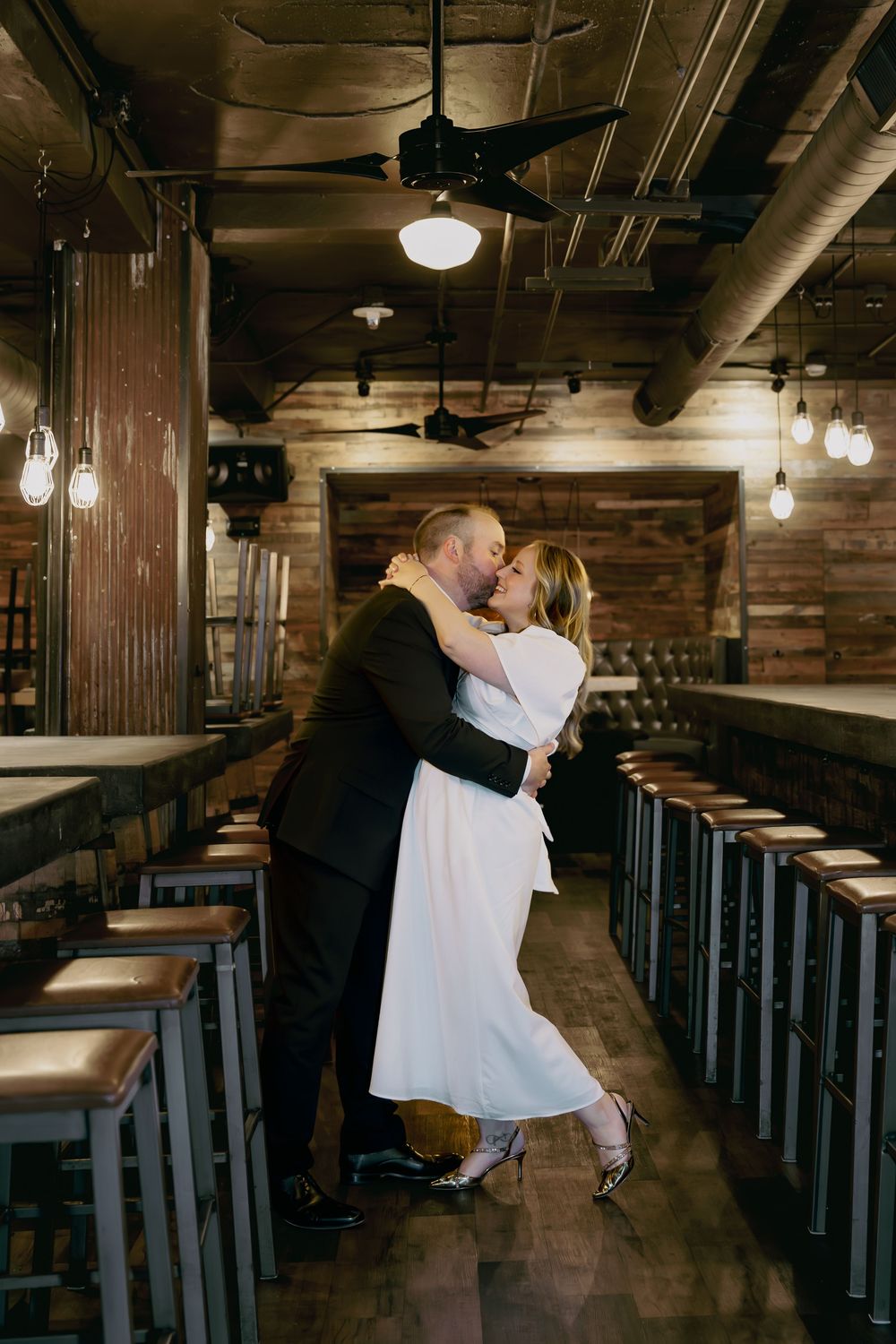 A romantic dance scene in an industrial-style restaurant with exposed brick walls, pendant lights and bar seating.