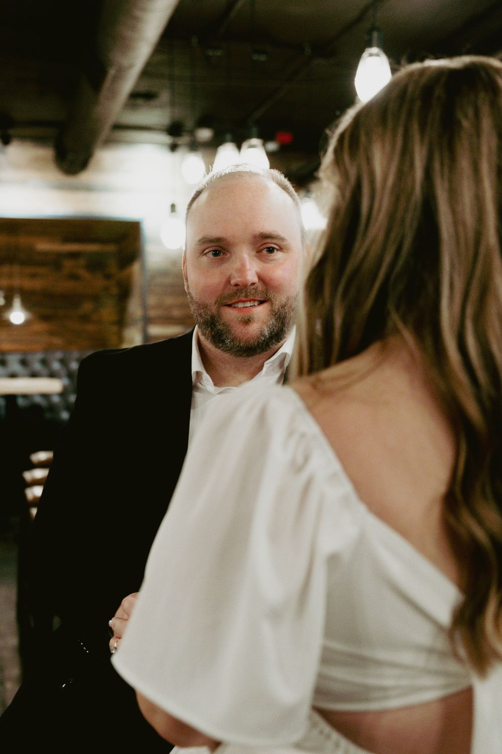 A couple shares an intimate moment at what appears to be a wedding reception in a dimly lit venue.
