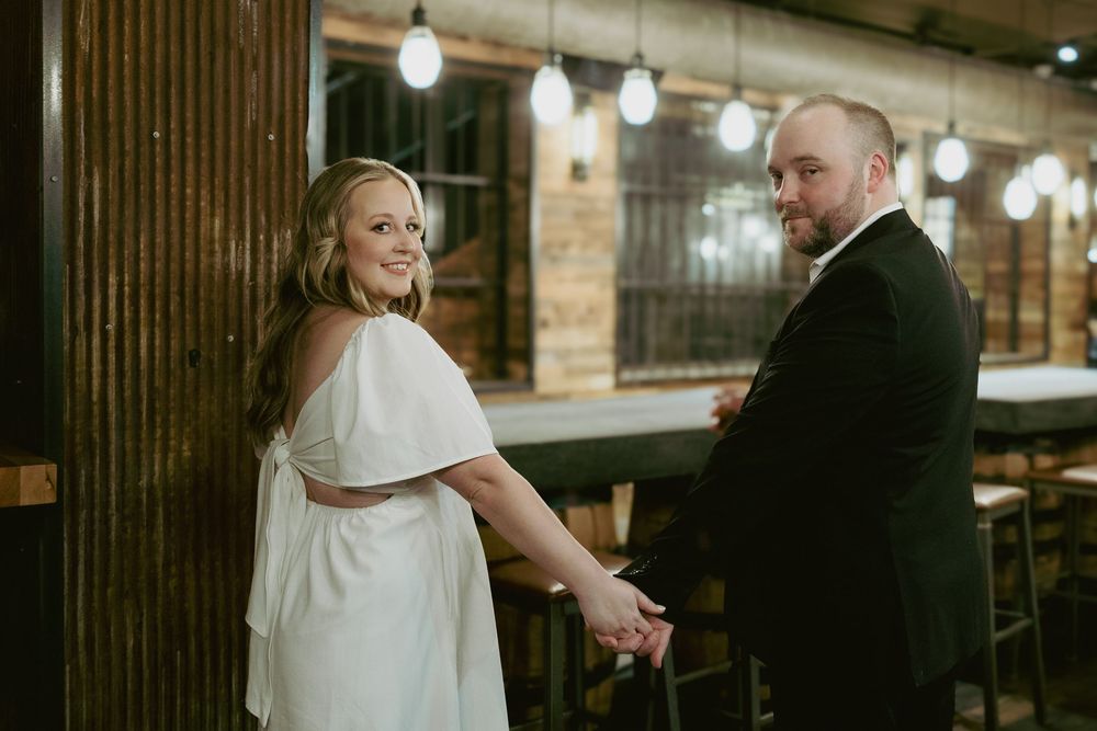 A couple shares a tender moment together in an indoor venue with warm lighting and wooden decor elements.
