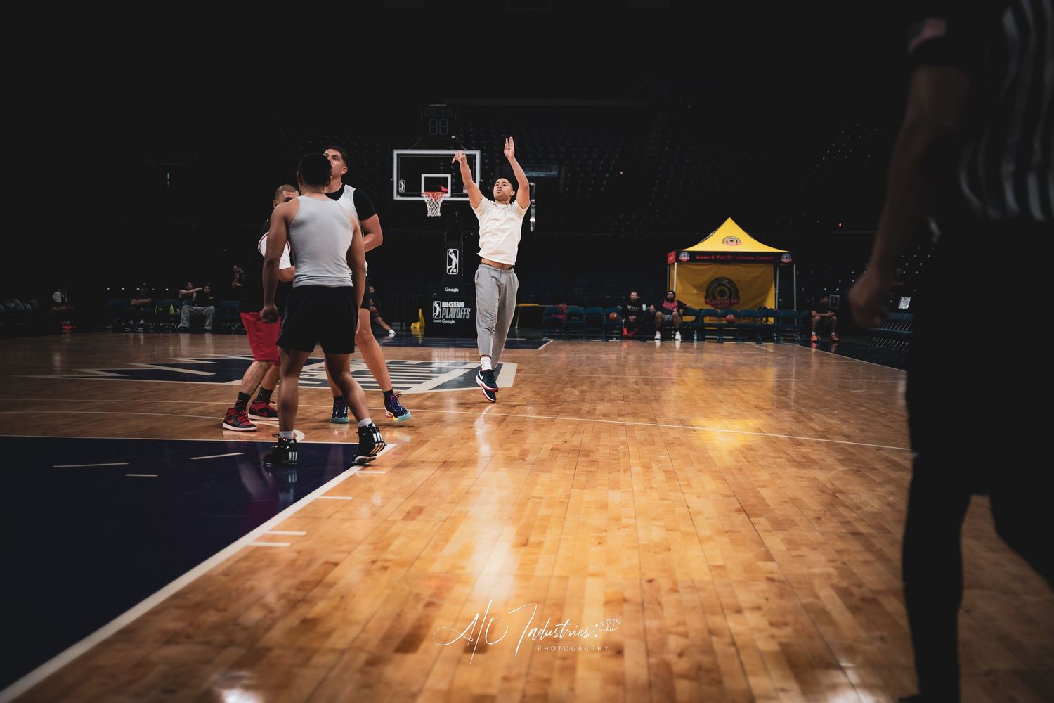 Players compete in a basketball game on a polished indoor court under bright lights during an evening tournament.