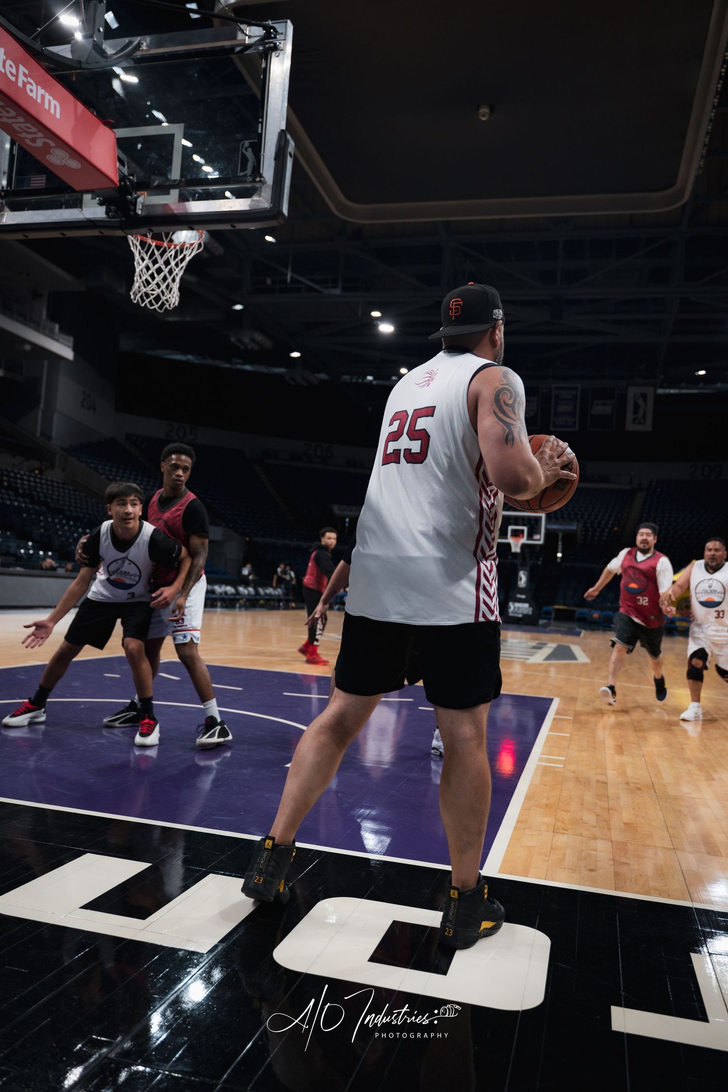 Basketball player wearing number 25 white jersey holds ball near court during indoor arena practice game.