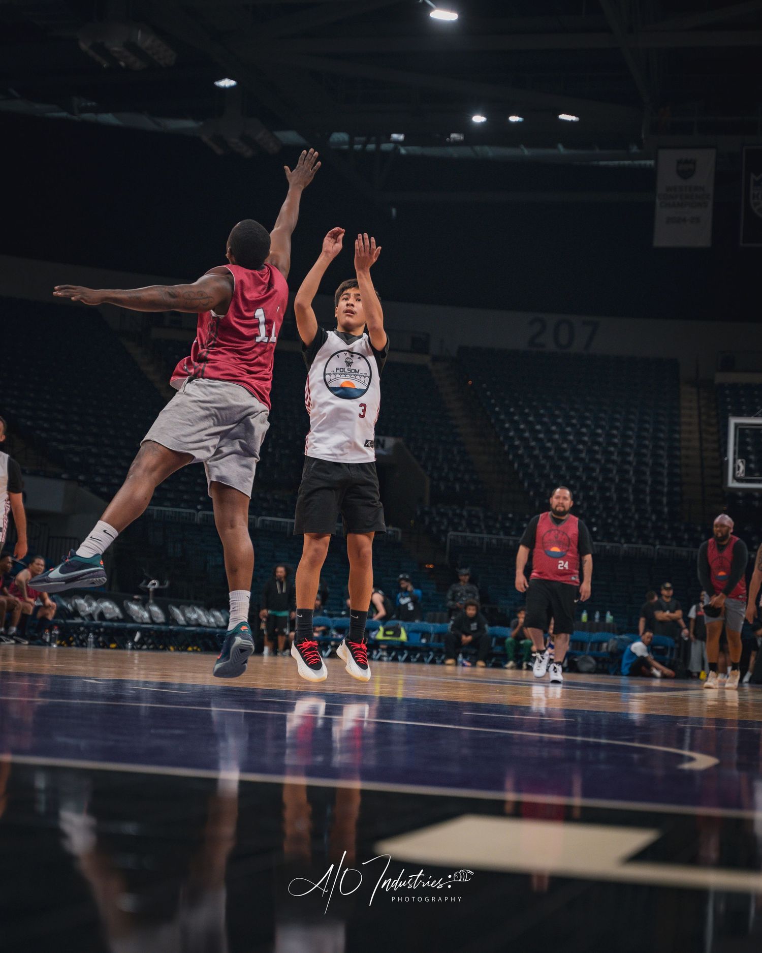 A player in jersey number 3 shoots over a defender during a basketball game in an indoor arena.