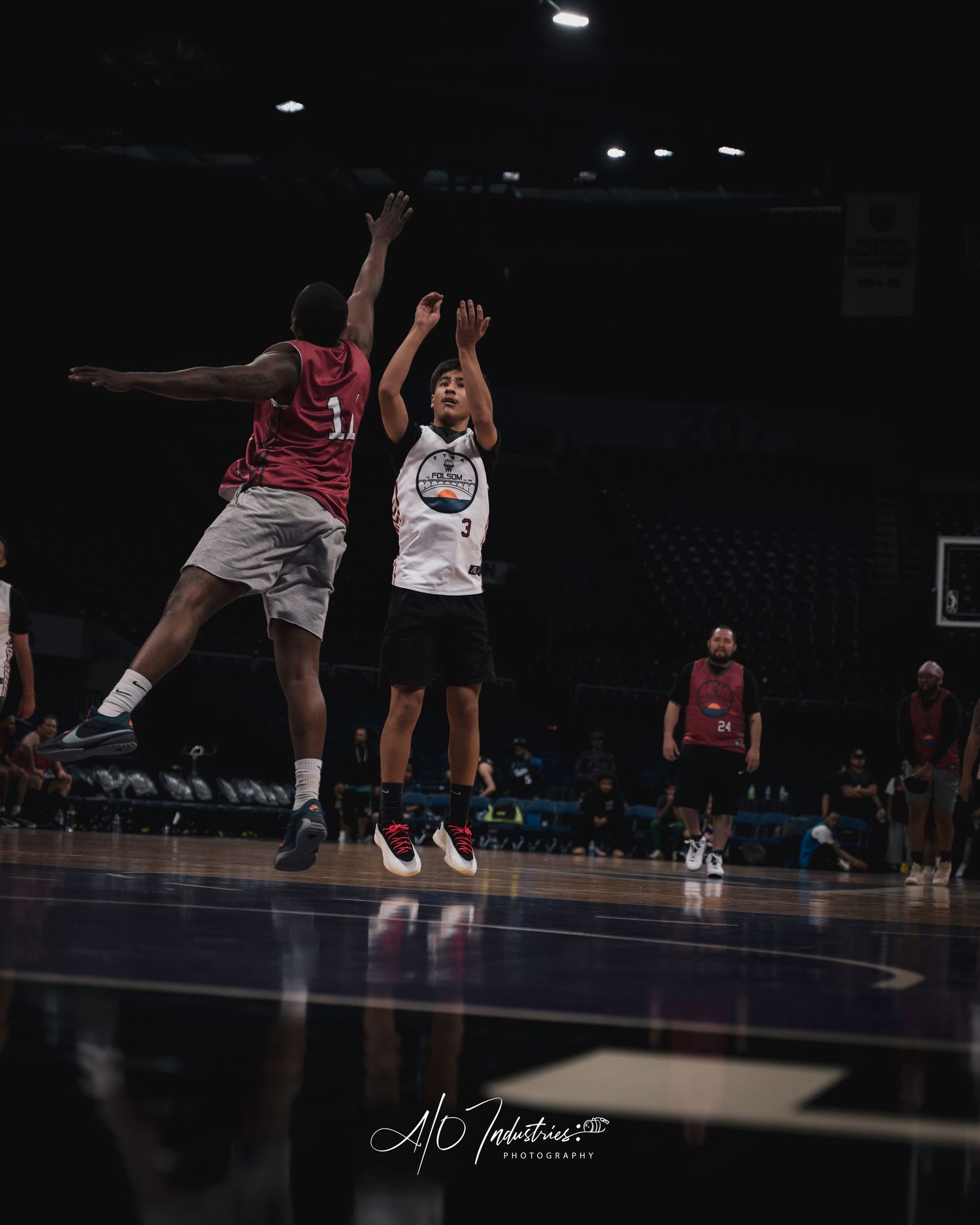 Basketball player wearing number 3 shoots a jump shot over a defender during an indoor arena game.