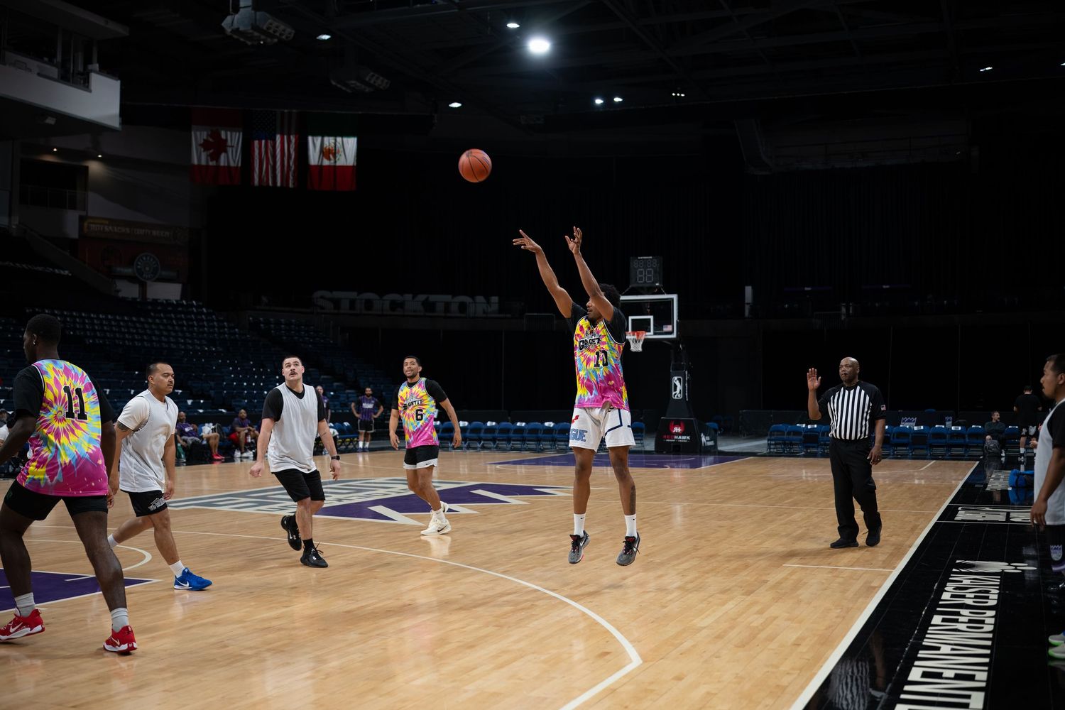 Players engaged in basketball practice drills on a well-lit indoor court.