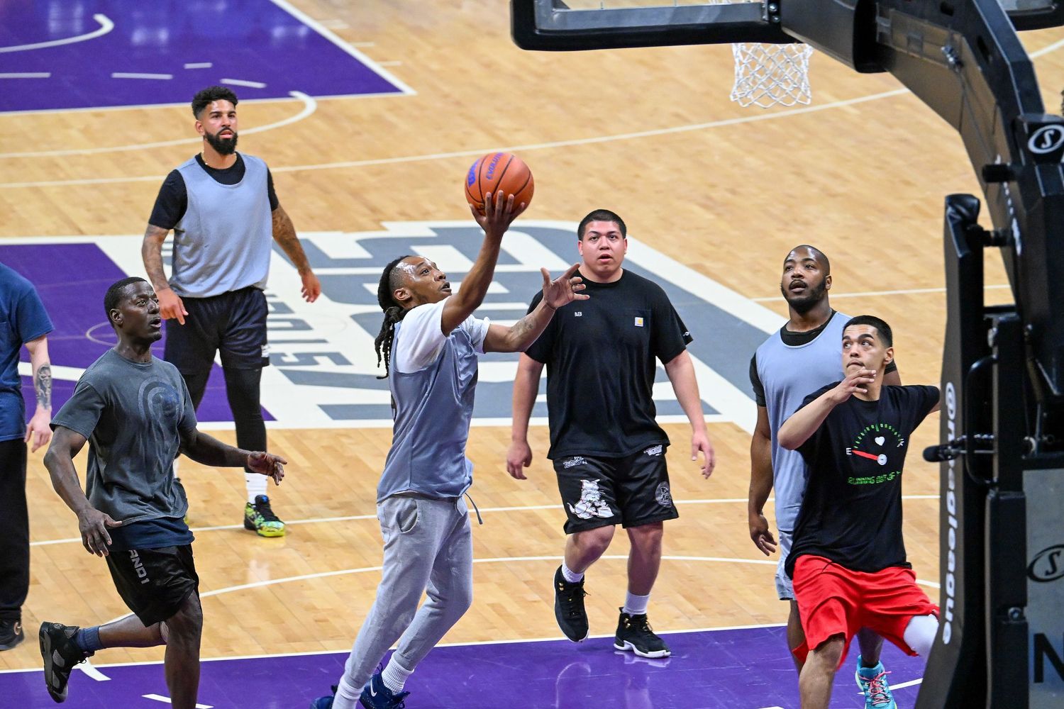 Athletes participating in basketball training exercises on a professional court with purple accents.