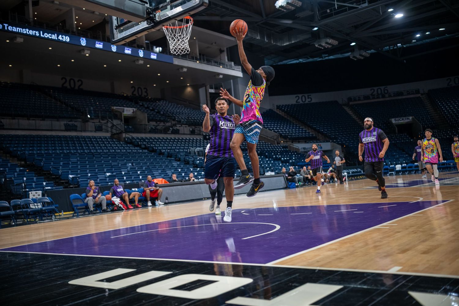 Basketball practice session with players spread across a professional arena court.