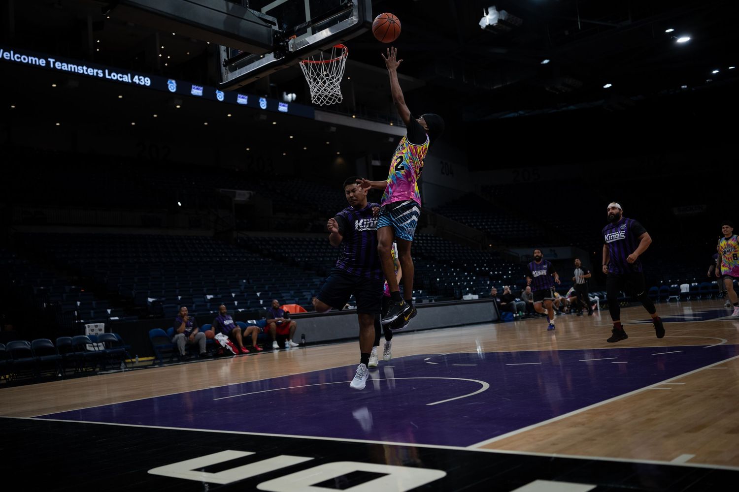 Basketball players running drills on a professional court during team practice.