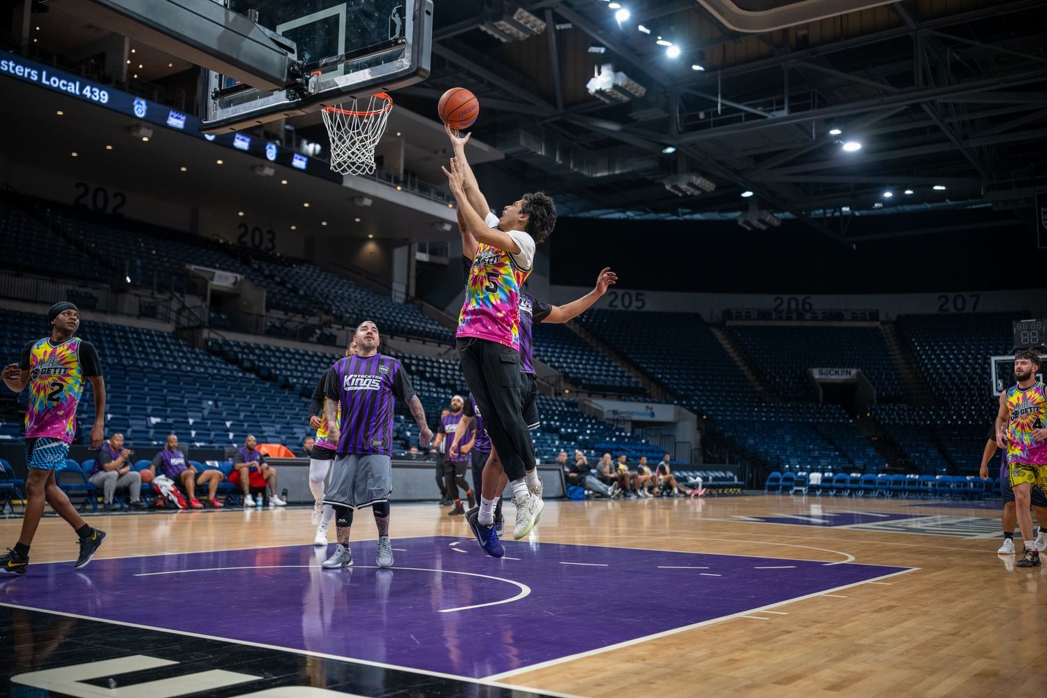 Athletes practicing basketball moves and skills on an indoor professional court.