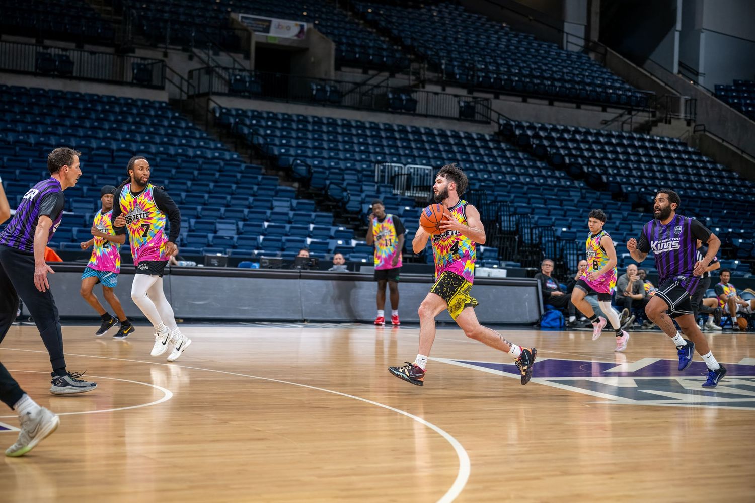 Basketball players engaged in practice drills across a professional arena floor.