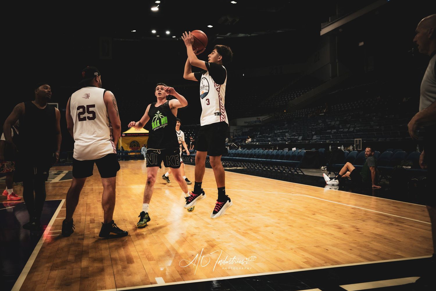 A player rises for a jump shot over a defender during an indoor basketball game.