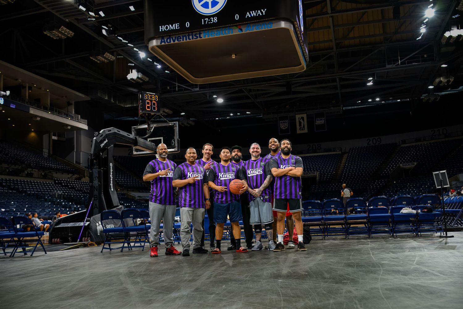 Team stands together for a group photo on a basketball court wearing matching purple jerseys.