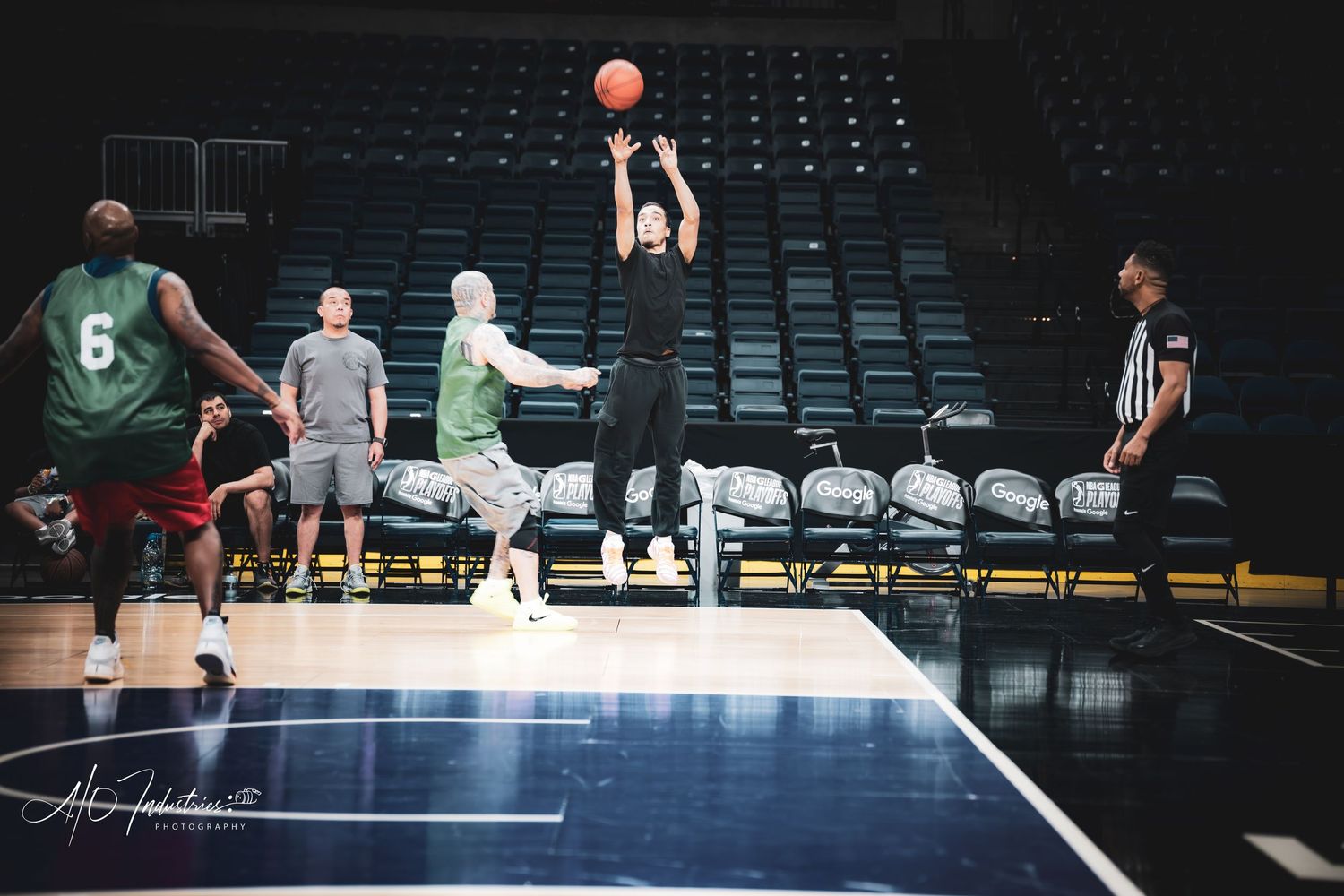 A player shoots a jump shot near the sideline during an indoor basketball practice game.