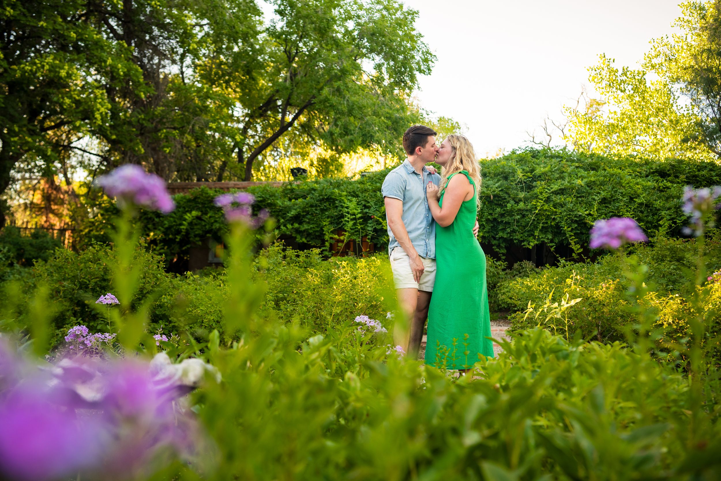 A romantic moment shared in a garden with purple wildflowers and golden evening light.