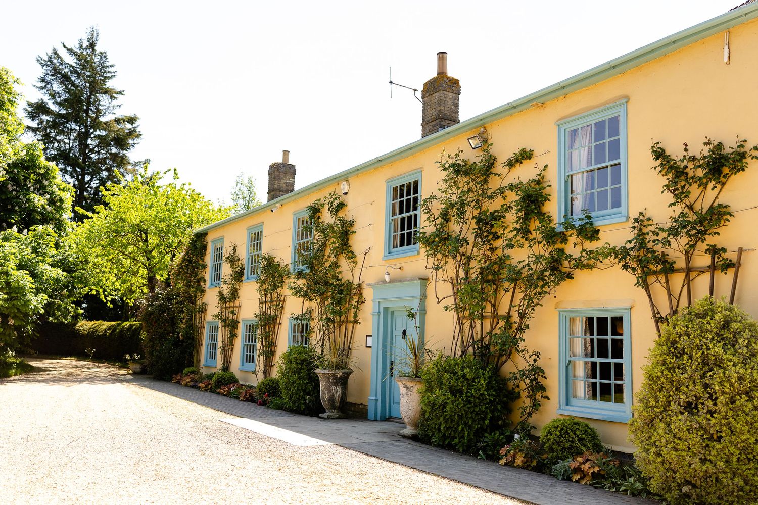 Historic stone manor hotel with classic Georgian architecture and manicured topiary gardens along entrance path.
