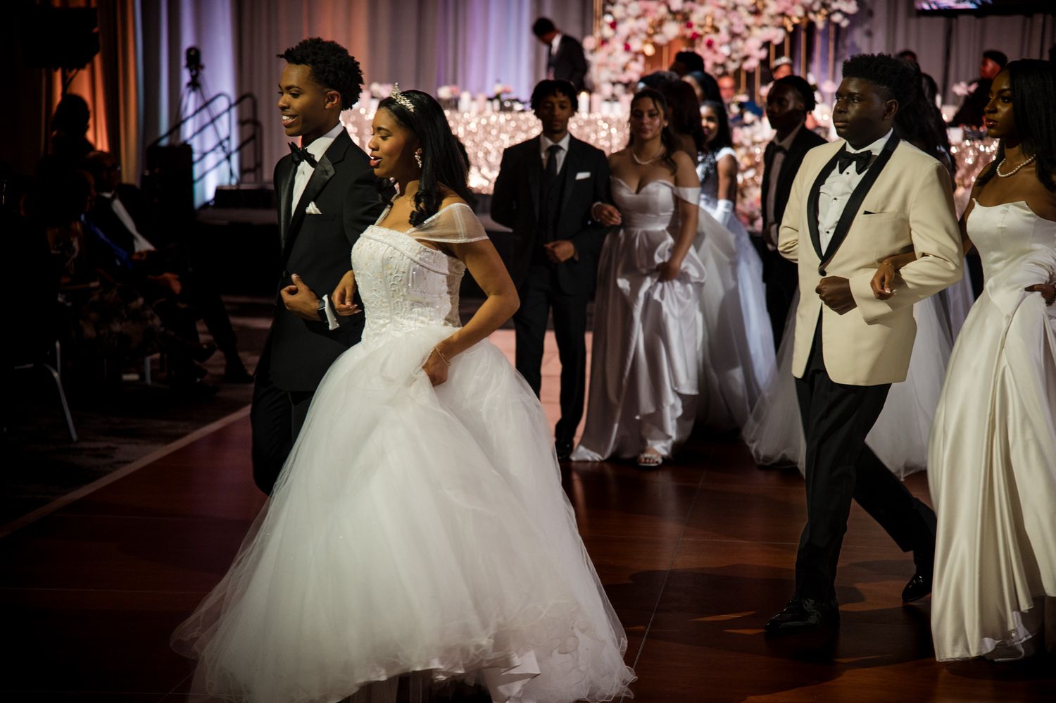 Bride in white ball gown dances with groom at elegant wedding reception with floral decor.