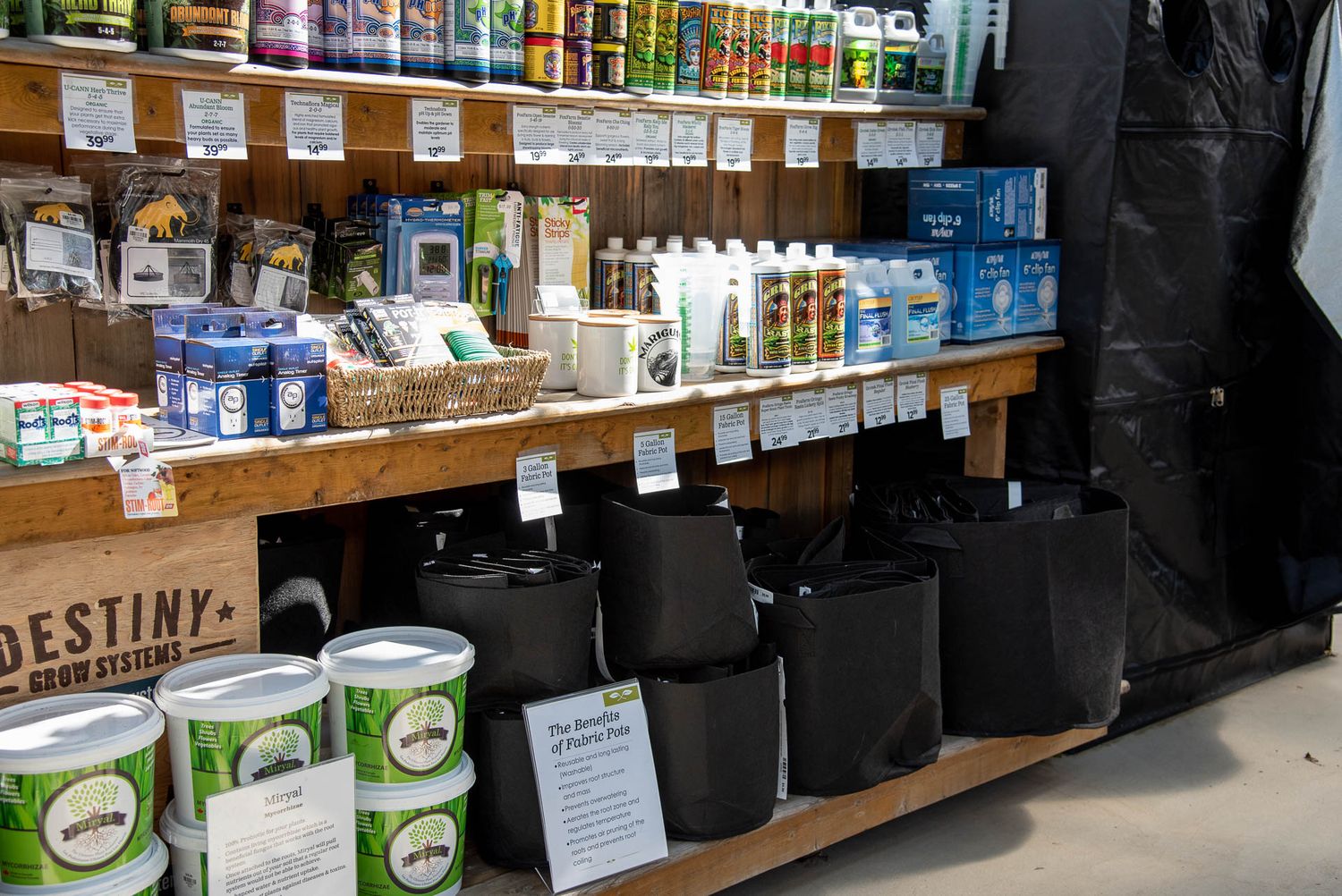 Garden supplies and plant nutrients displayed on wooden shelves with black containers at Bradford Greenhouse in Barrie, ON
