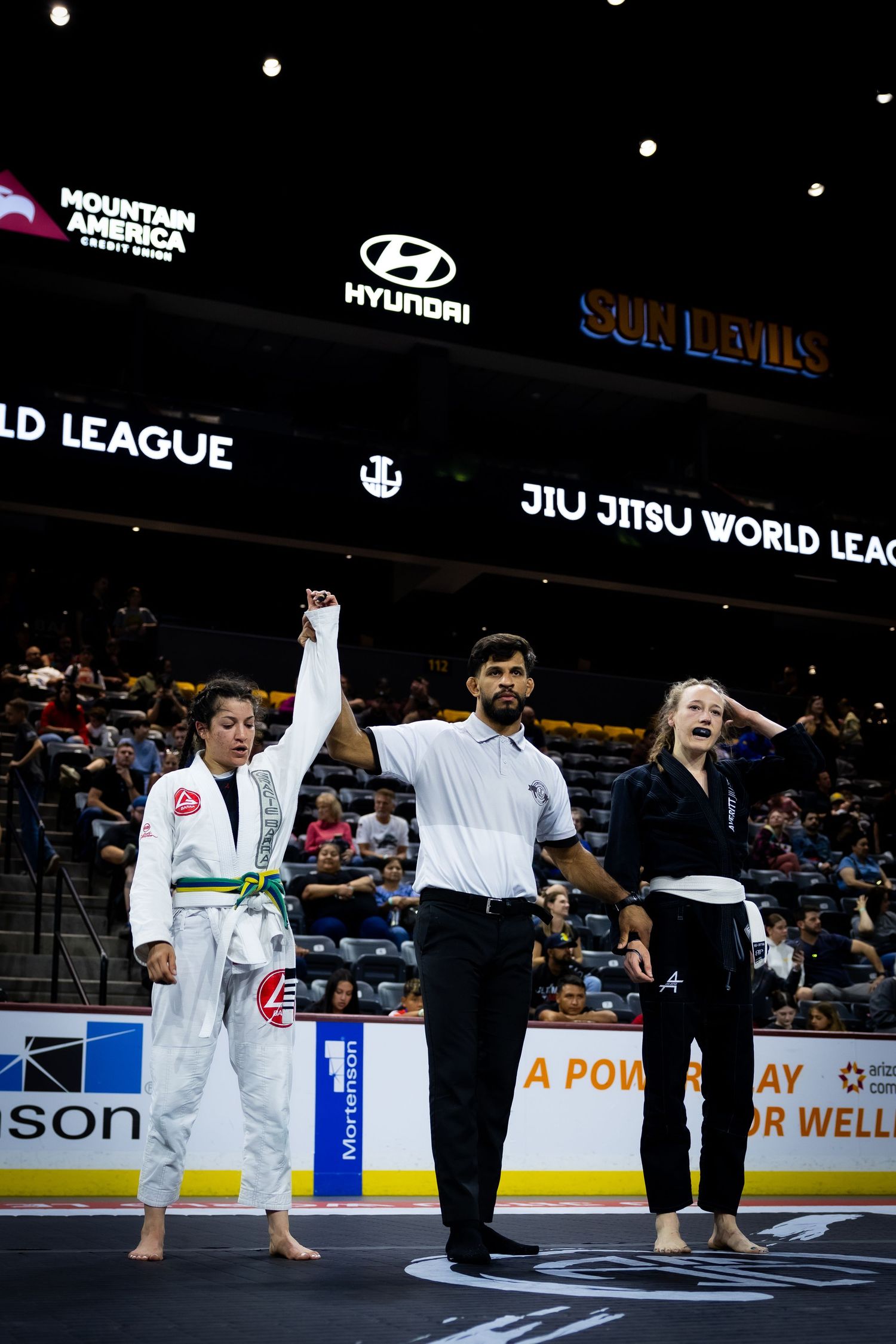 Athletes and officials stand on the competition floor during a martial arts tournament ceremony.