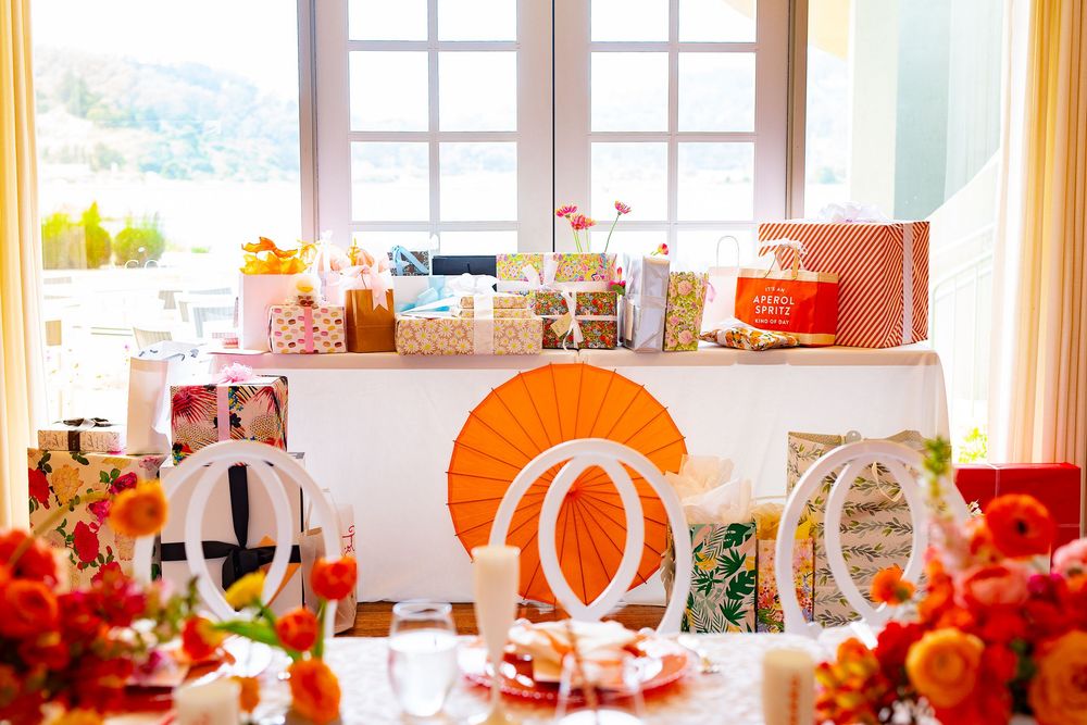 Elegant gift station with orange decor and floral arrangements near a bright window.