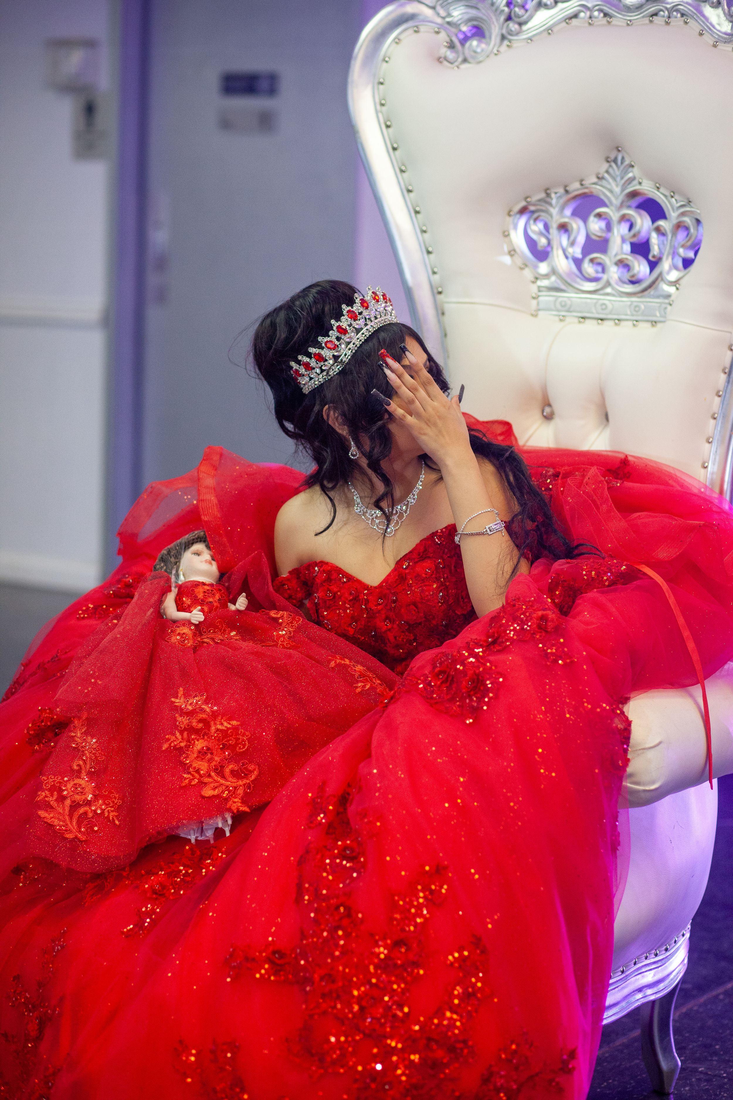 Ornate white throne chair with purple accents showcases a flowing red sparkle gown.