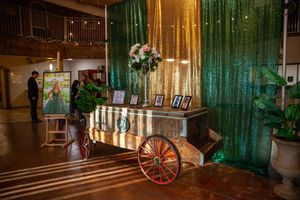 An elegant event venue with green and gold curtains and vintage decor.