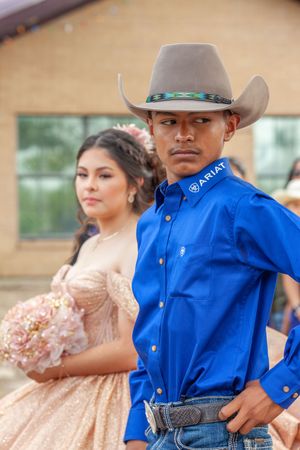 Dancers in western attire with blue shirts and cowboy hats pose outdoors.