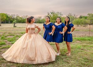 Outdoor quinceanera photo shoot with blue-dressed attendants and peach ballgown.