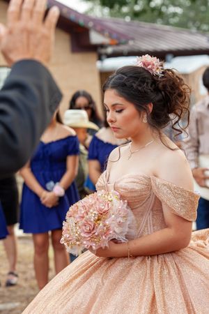 Rose gold quinceañera dress details with delicate embellishments and floral bouquet.