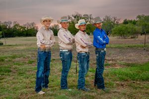 Group photo of western-styled attendants in blue shirts and jeans on rural background.