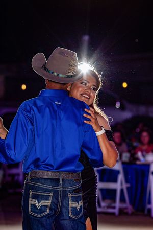 Western-themed dance celebration with blue shirts and cowboy hats in evening lighting.