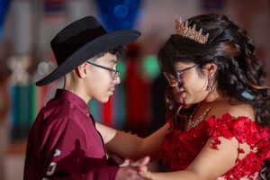 Dancers in formal attire perform traditional dance moves at a celebration event.