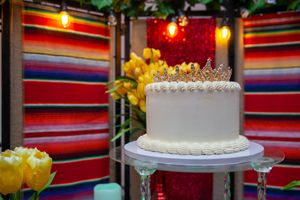 Festive party setup with colorful serape-style decorations and white celebration cakes.