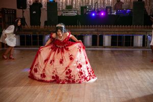 Spacious ballroom decorated for a formal celebration with dramatic lighting and wooden floors.