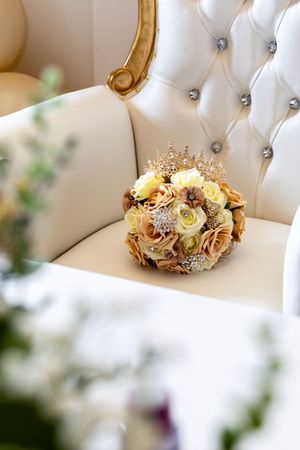 Decorative crown and floral arrangement displayed on white tufted furniture.