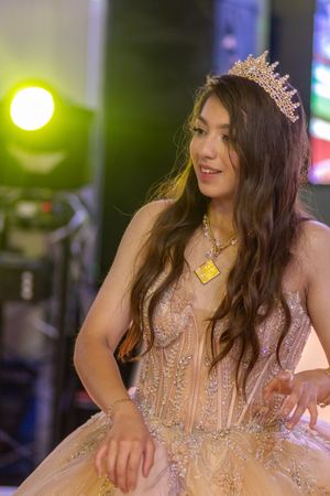 Elegant celebration scene with someone wearing a crown and champagne-colored embellished gown.