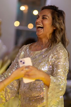 Person in a sparkly gold dress laughing joyfully during a celebration.