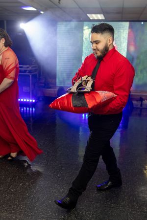 Dancers perform in coordinated red and black outfits under blue stage lighting.