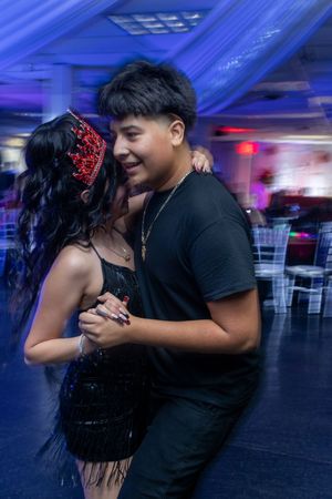 Couples dancing together at a celebration event under blue ambient lighting.