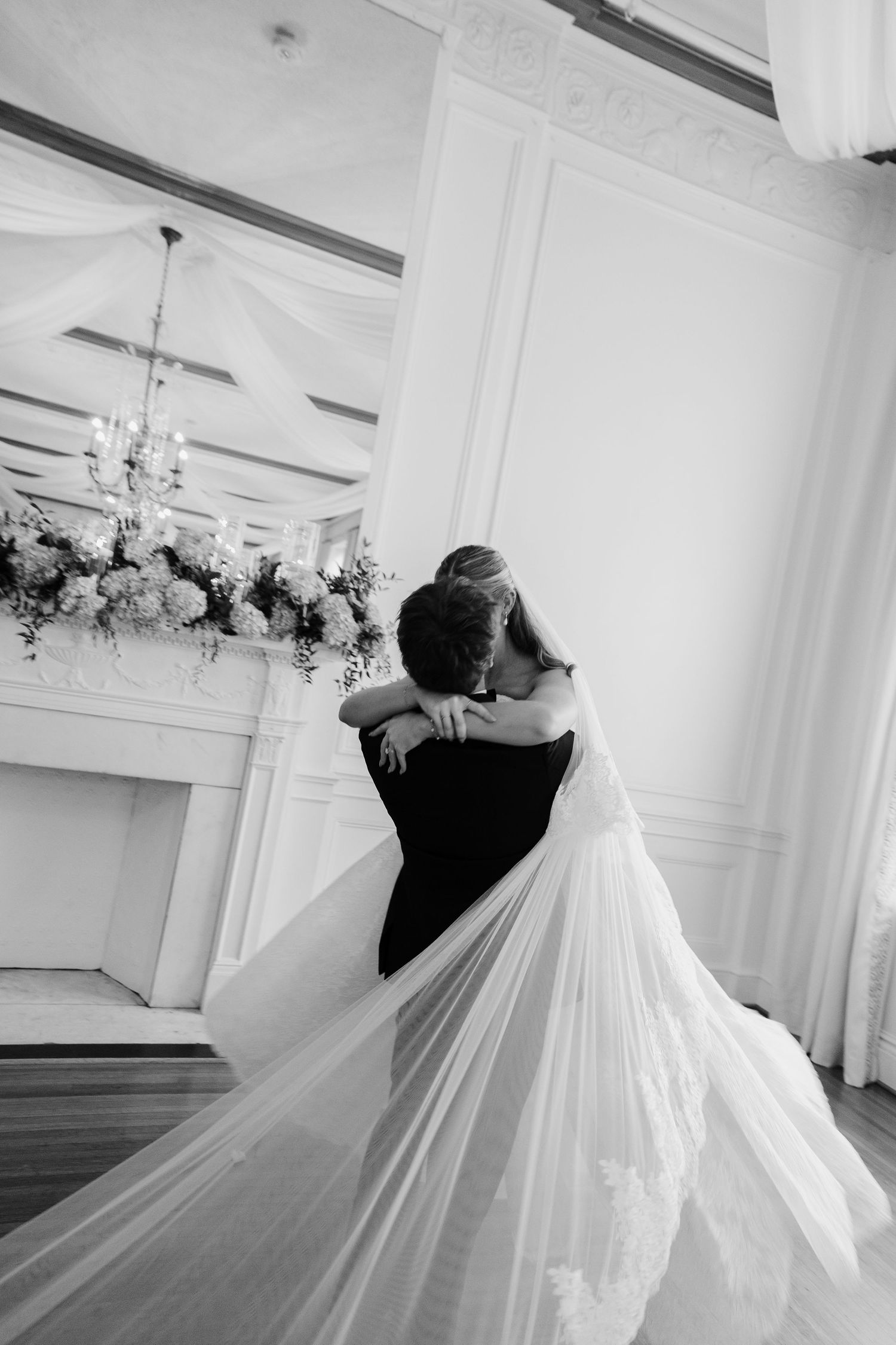 Groom spinning the bride while holding her in his arms. Black and white photo.