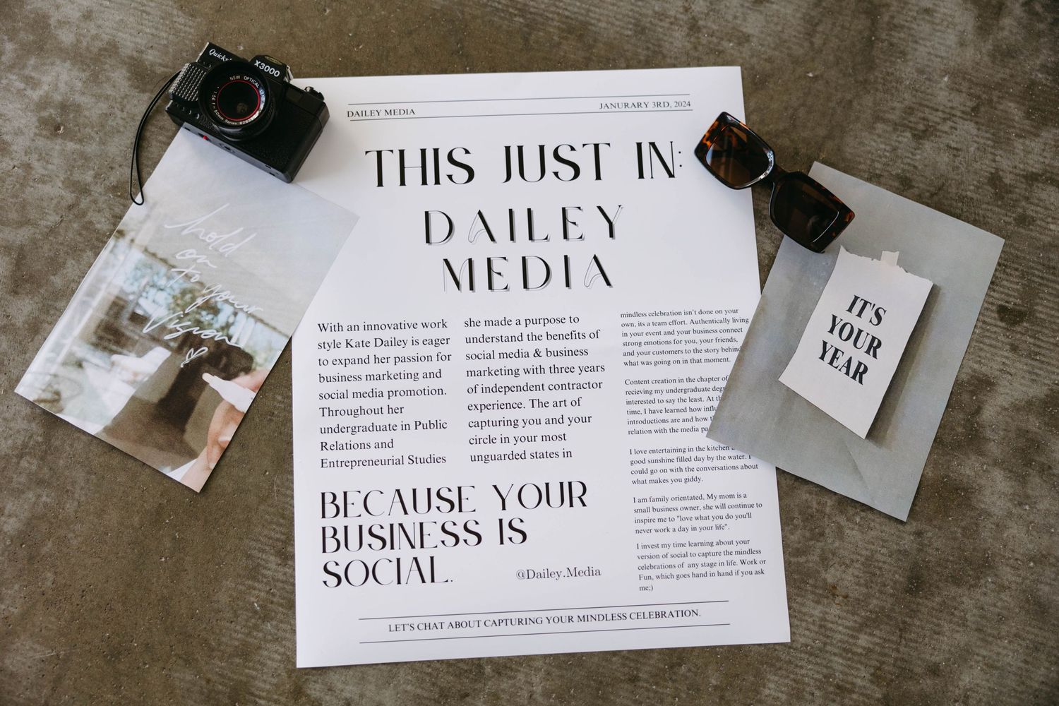 Flatlay of business media document with vintage cameras and notes on concrete surface.