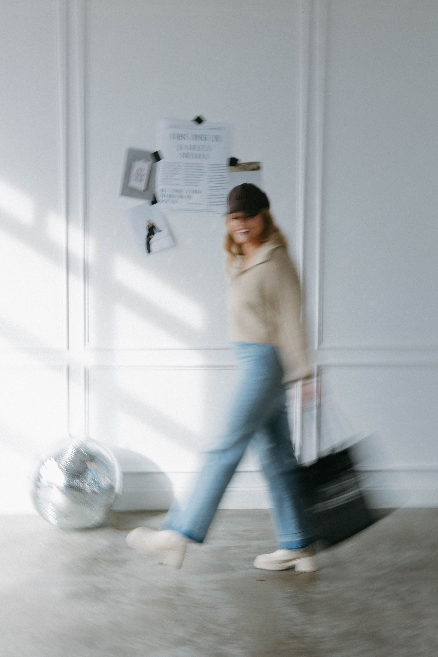 Motion blur photo showing movement past a silver disco ball and bulletin board in a bright room.
