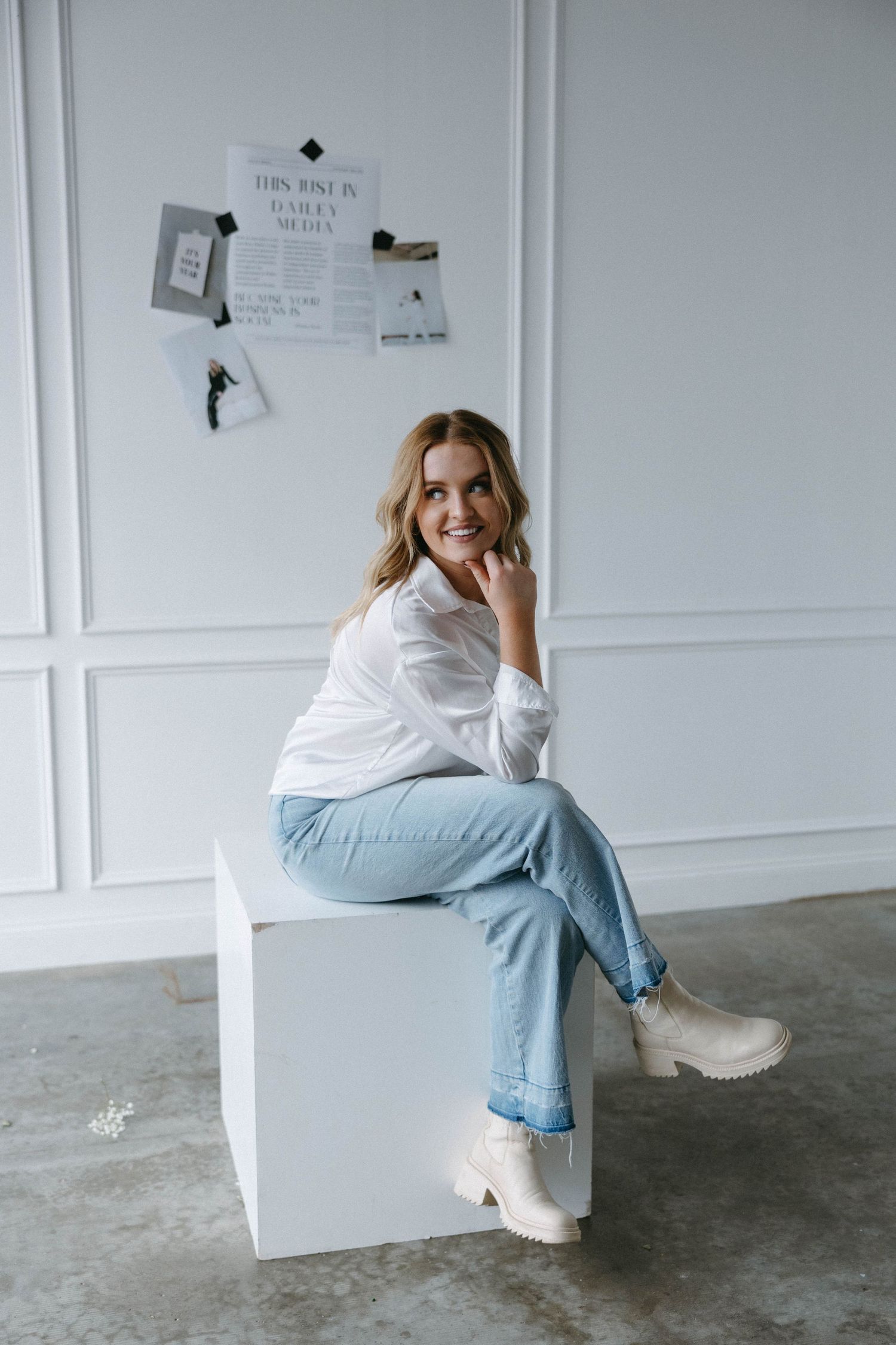 Lifestyle photo of casual fashion with light denim and white boots against white paneled wall.