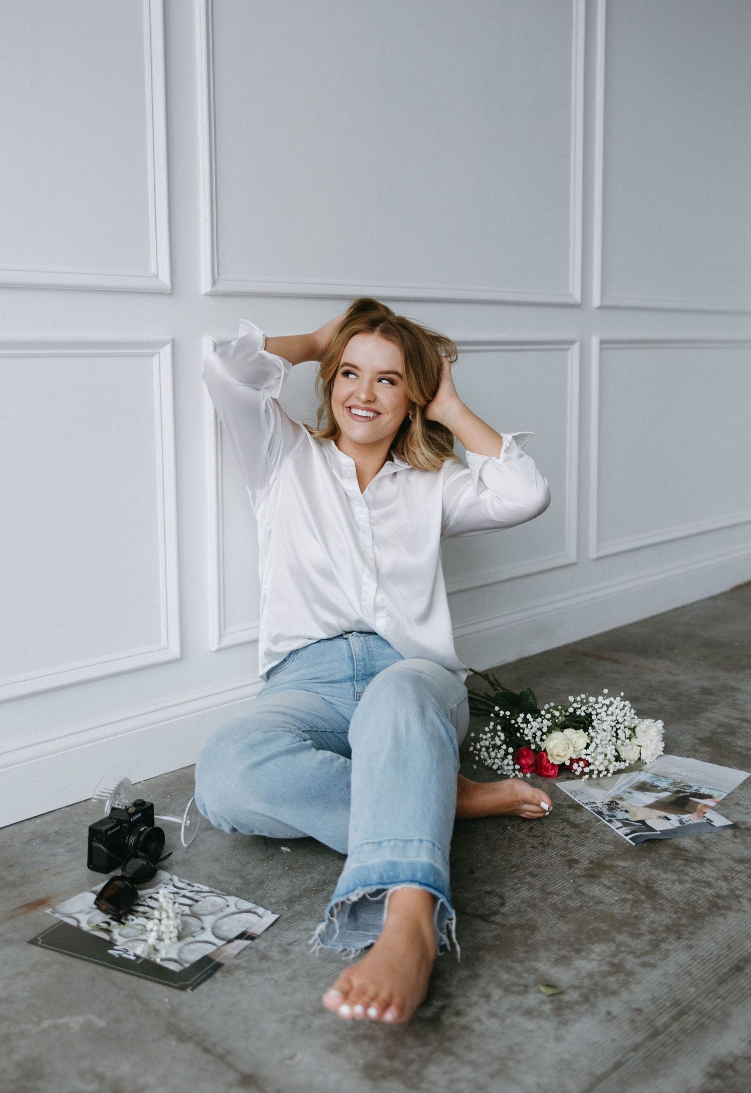 Lifestyle portrait in white button-down shirt and jeans against decorative wall panels.
