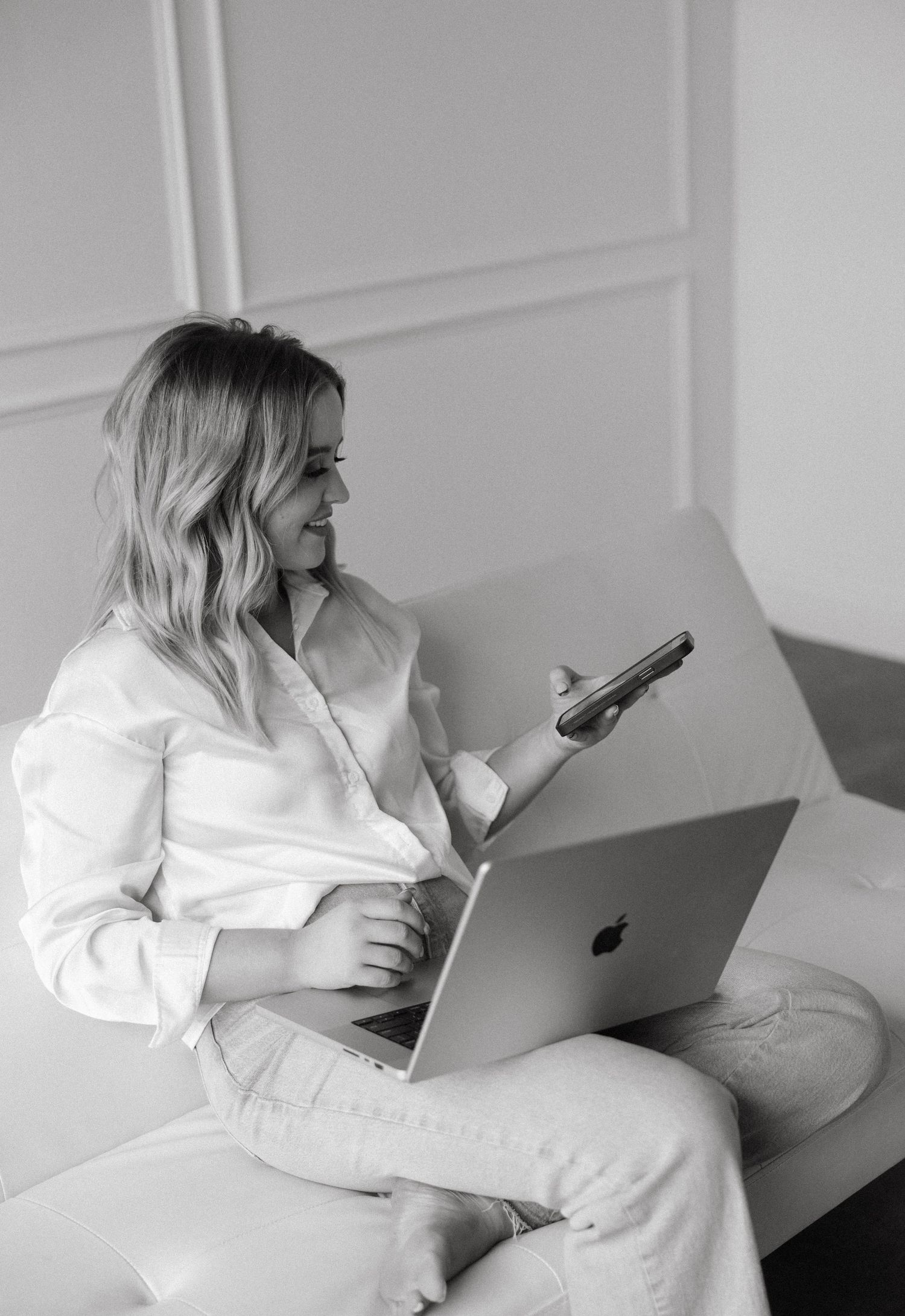 Modern workspace setup with laptop and phone against white paneled wall background.